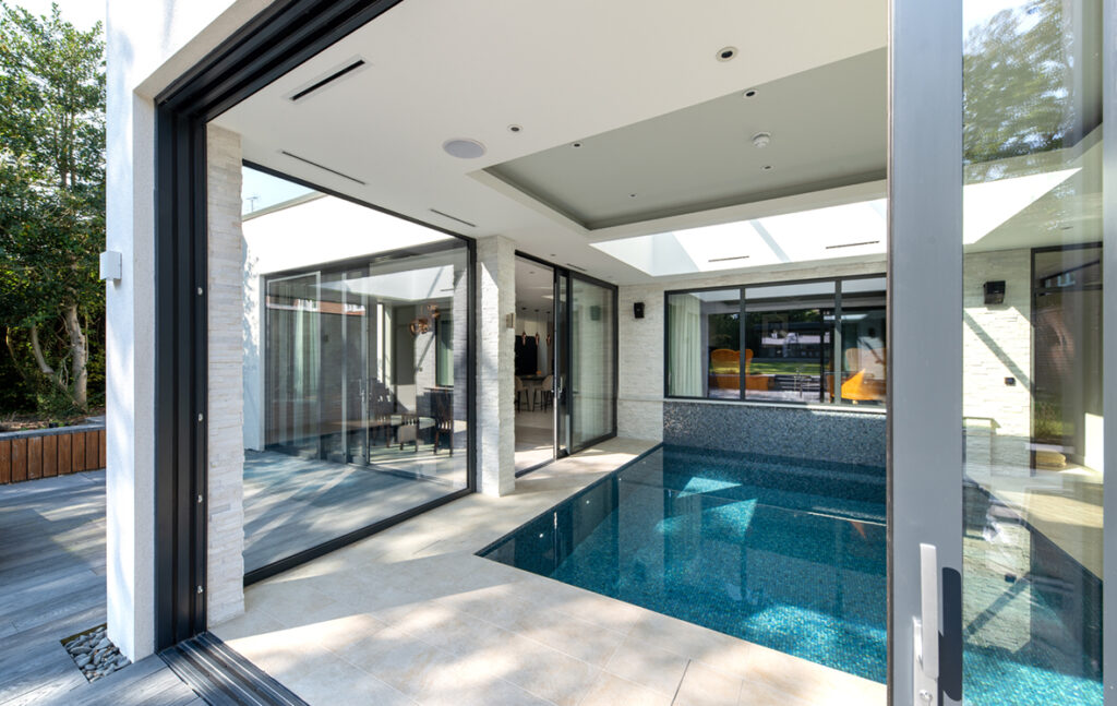 glass pool enclosure with two sets of sliding doors and a fixed window